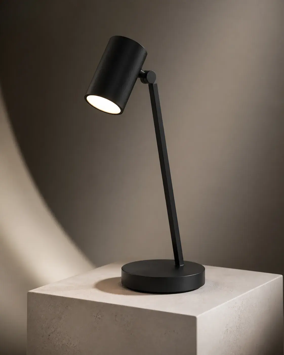 Premium 3D product render of a minimalist matte-black desk lamp on a pale stone pedestal, dramatic softbox lighting, a clean 