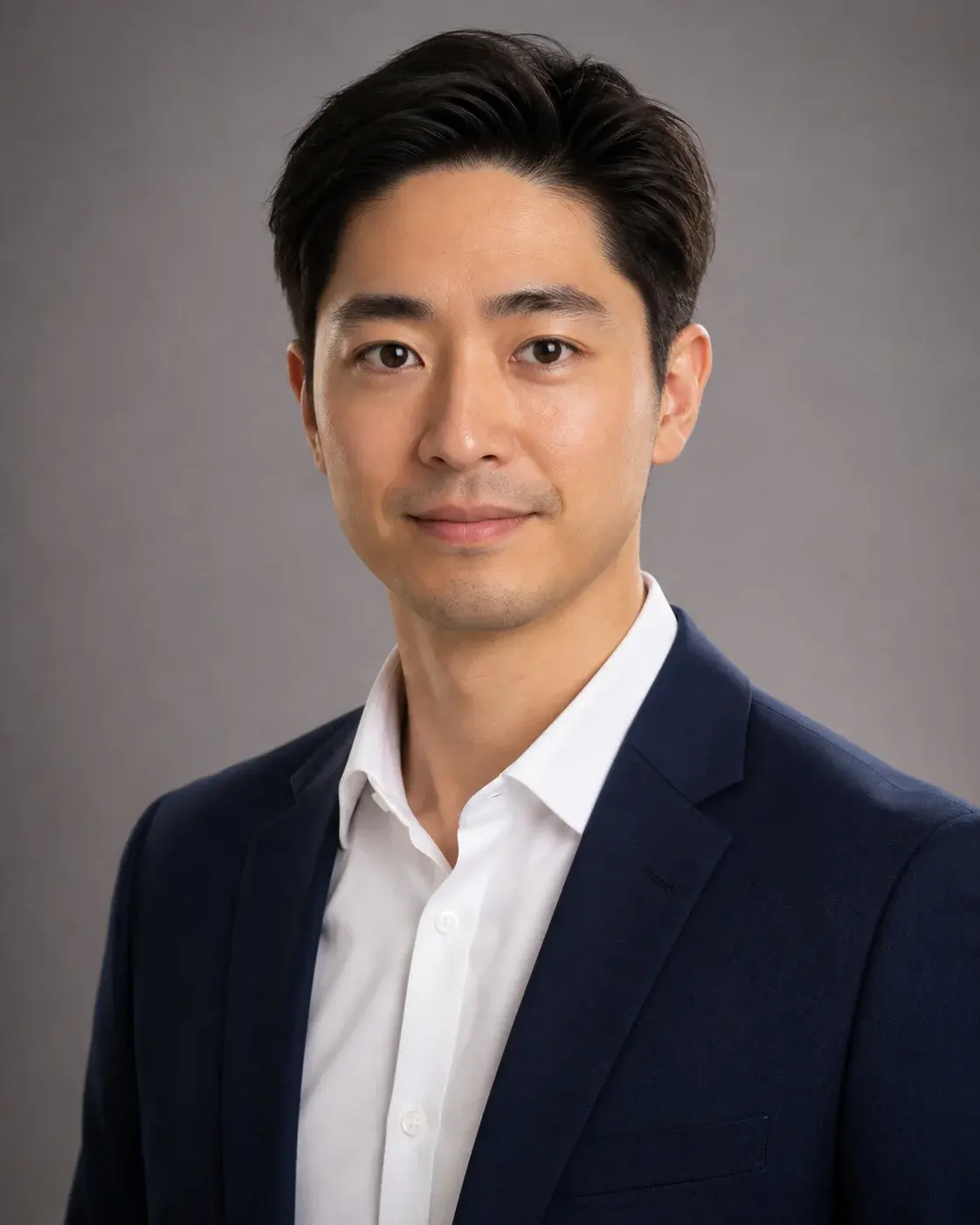A professional corporate headshot of a fictional adult East Asian man in his early 30s wearing a navy blazer and crisp white 